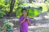Girl playing in field with giant leaf